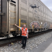Image of Gregory Kleynerman, Founder and CEO of Redflag Cargo Security Systems LLC in front of an intermodal rail car